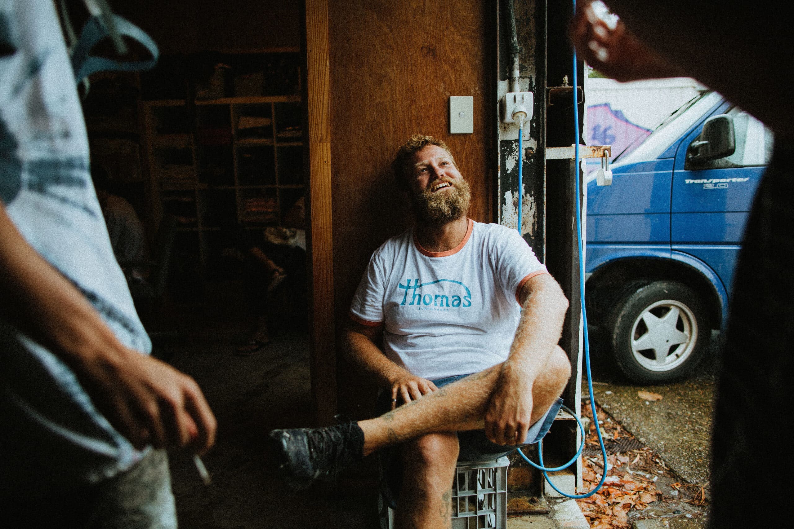 Shapers-Club- Un homme barbu assis dans un garage. -surfshop-surfboard