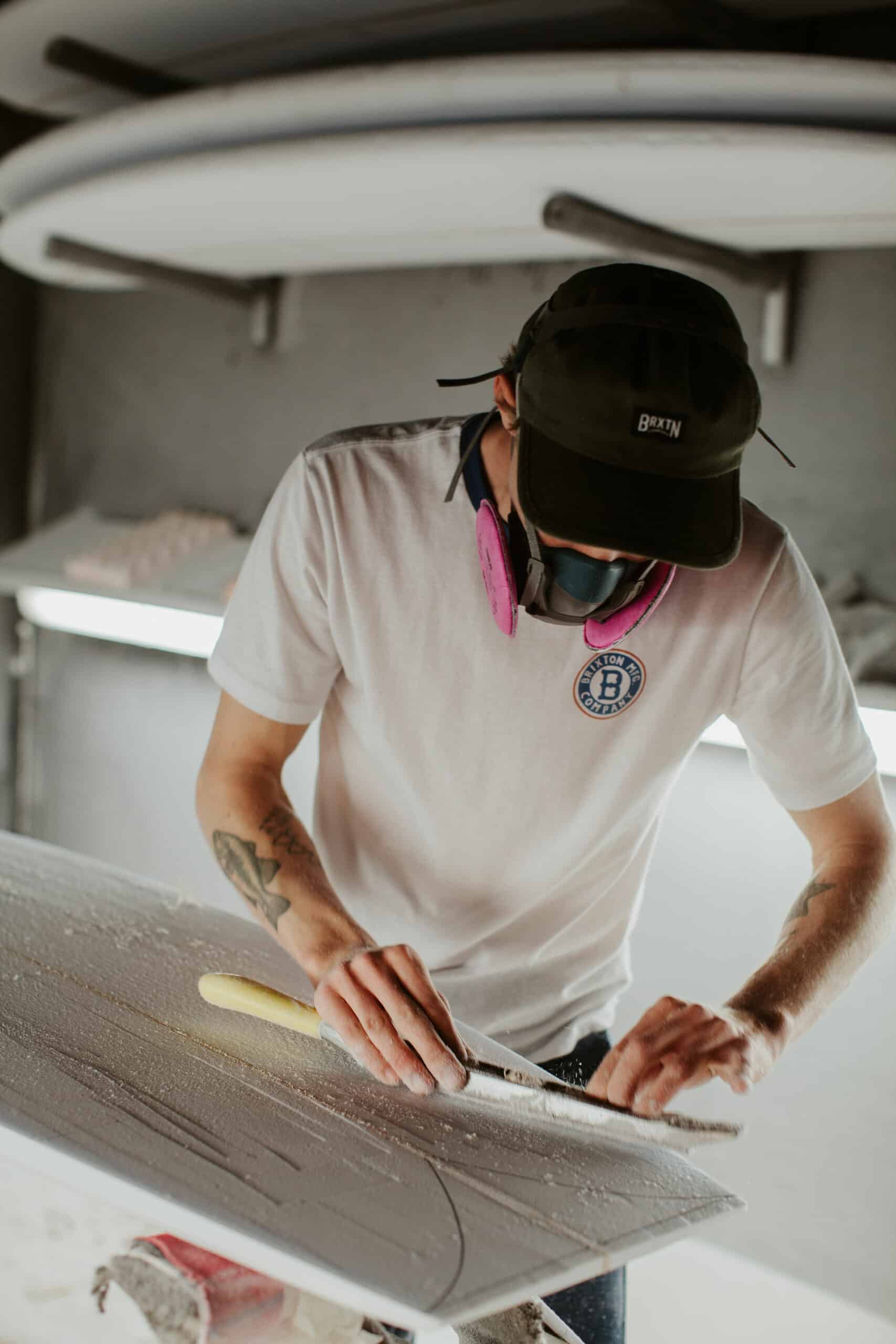 Shapers-Club- Un homme travaille sur une planche de surf dans un atelier. -surfshop-surfboard